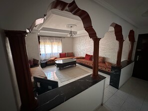 A spacious living room with a sofa set, a coffee table, and a dining table.