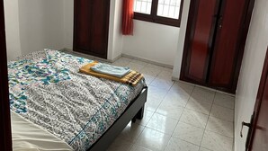 A bedroom with a bed, two wardrobes, a window with curtains, and a ceiling fan.