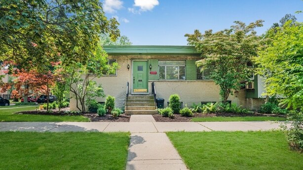 A two-story house with a green door, a front porch, and a small front yard with a sidewalk leading to the entrance. - Spacious 3 Bedroom 1 Bathroom  Rogers Park Town House Budget-Friendly (Chicago)