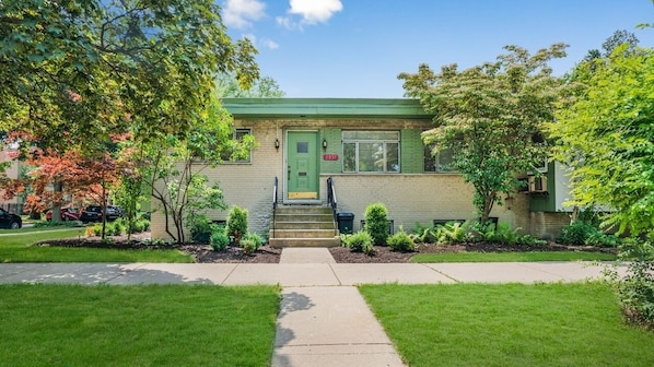 A two-story house with a green door, a front porch, and a small front yard with a sidewalk leading to the entrance. - Spacious 3 Bedroom 1 Bathroom Rogers Park Town House Budget-Friendly (Chicago)