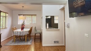 A dining area with a table and chairs, a vase with flowers, and a wall-mounted TV. - Spacious 3 Bedroom 1 Bathroom  Rogers Park Town House Budget-Friendly (Chicago)