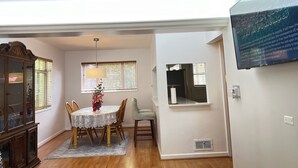 A dining area with a round table, chairs, a vase of flowers, and a window with blinds. - Spacious 3 Bedroom 1 Bathroom  Rogers Park Town House Budget-Friendly (Chicago)
