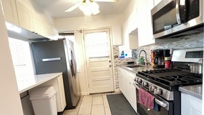 A compact kitchen with a refrigerator, stove, microwave, and a small sink. - Spacious 3 Bedroom 1 Bathroom  Rogers Park Town House Budget-Friendly (Chicago)