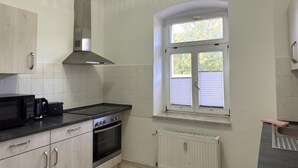 Eine Küche mit Herd, Backofen, Mikrowelle und einem Fenster mit Jalousien.