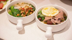 Deux bols de soupe contenant de la viande et des légumes, et un objet rouge en arrière-plan.
