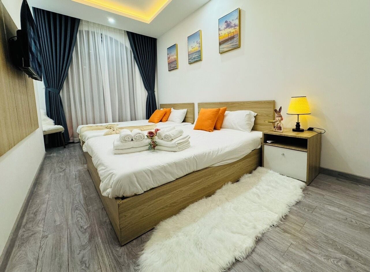 A hotel room with a large bed, a bedside table with a lamp, and a fluffy rug.