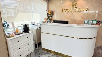 A reception desk with a marble floor, a window with blinds, and a wall-mounted sign that reads "ICON HOME".