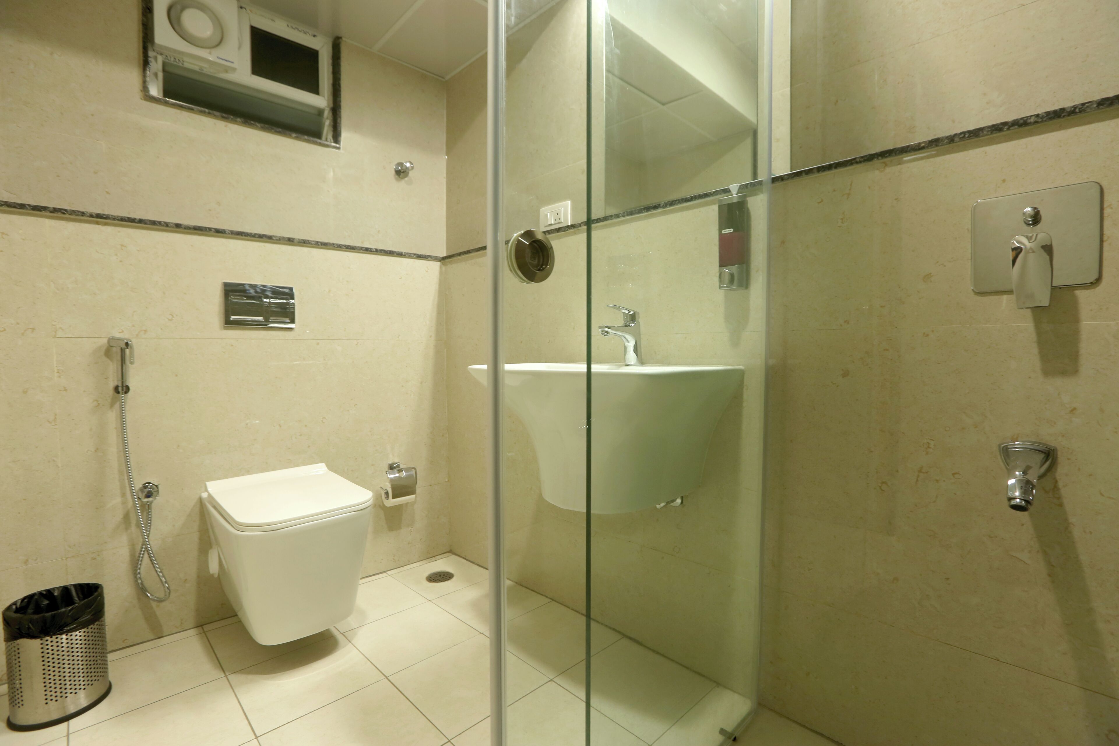 A bathroom with a glass-enclosed shower, a white sink, and a toilet.