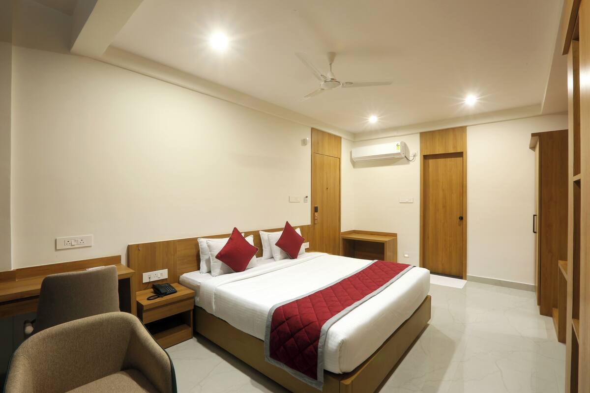 A hotel room with a bed, a desk, a chair, a wardrobe, and a ceiling fan.