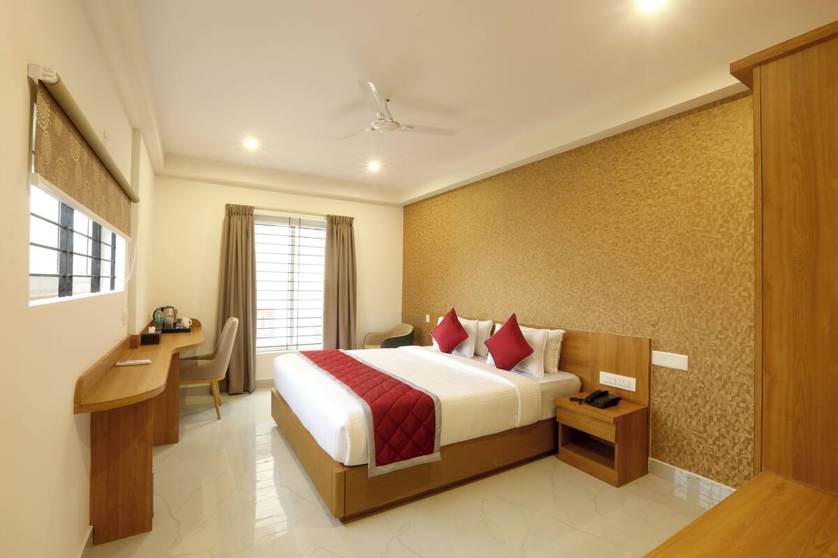 A hotel room with a large bed, bedside tables, a desk, and a chair.