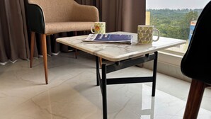 Ein Zimmer mit einer Couch, einem Tisch mit einer Zeitschrift, einer Tasse und Blick ins Grüne.