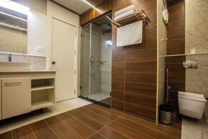 A modern bathroom with a glass shower enclosure, a white toilet, and a vanity with a mirror and sink. - The Hoften Sterling Plaza Near Kempegowda International Airport (Bengaluru)