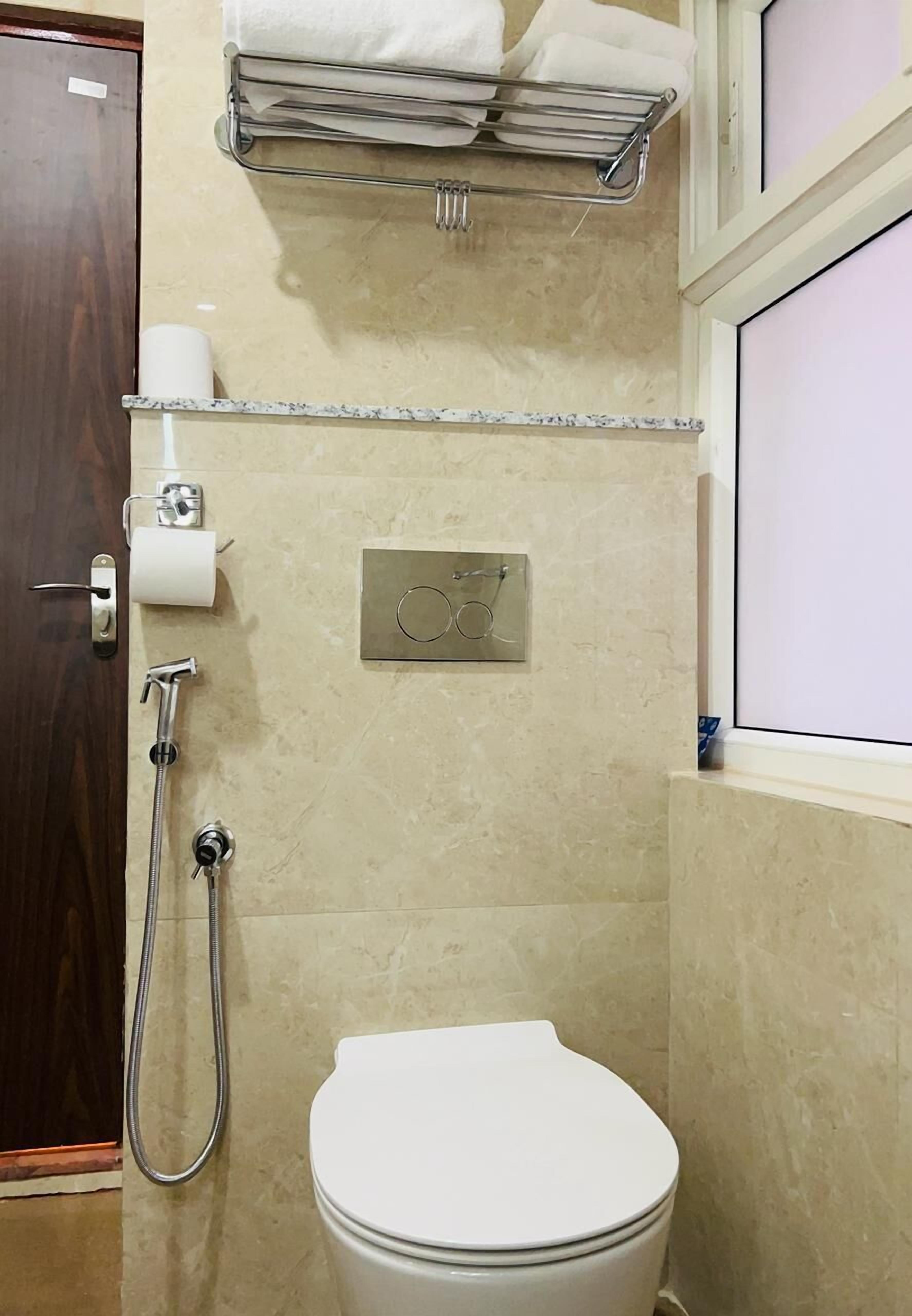 A bathroom with a toilet, a shower, and a towel rack.