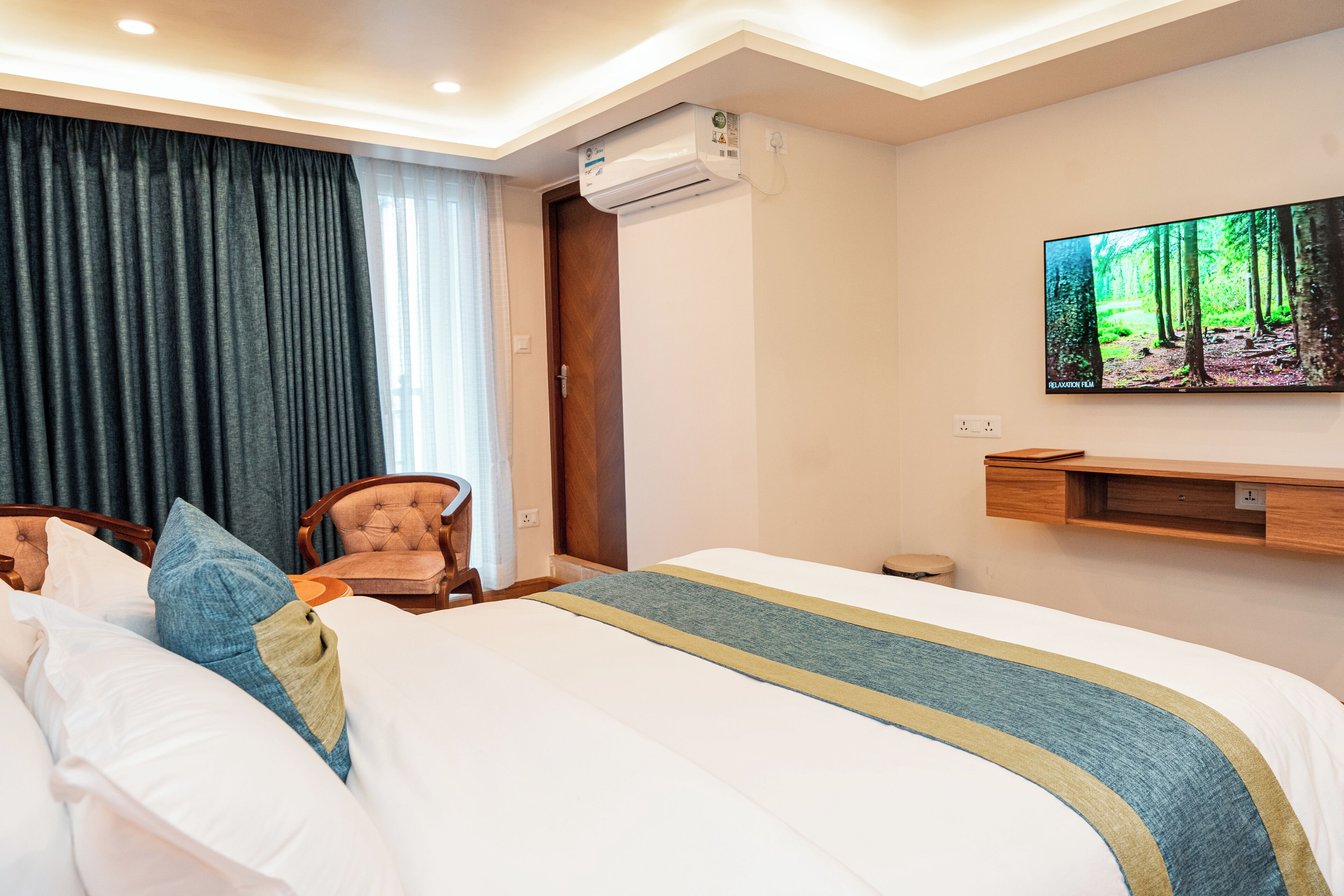 Una camera d'albergo con un letto, una sedia, una televisione e una mensola a parete.