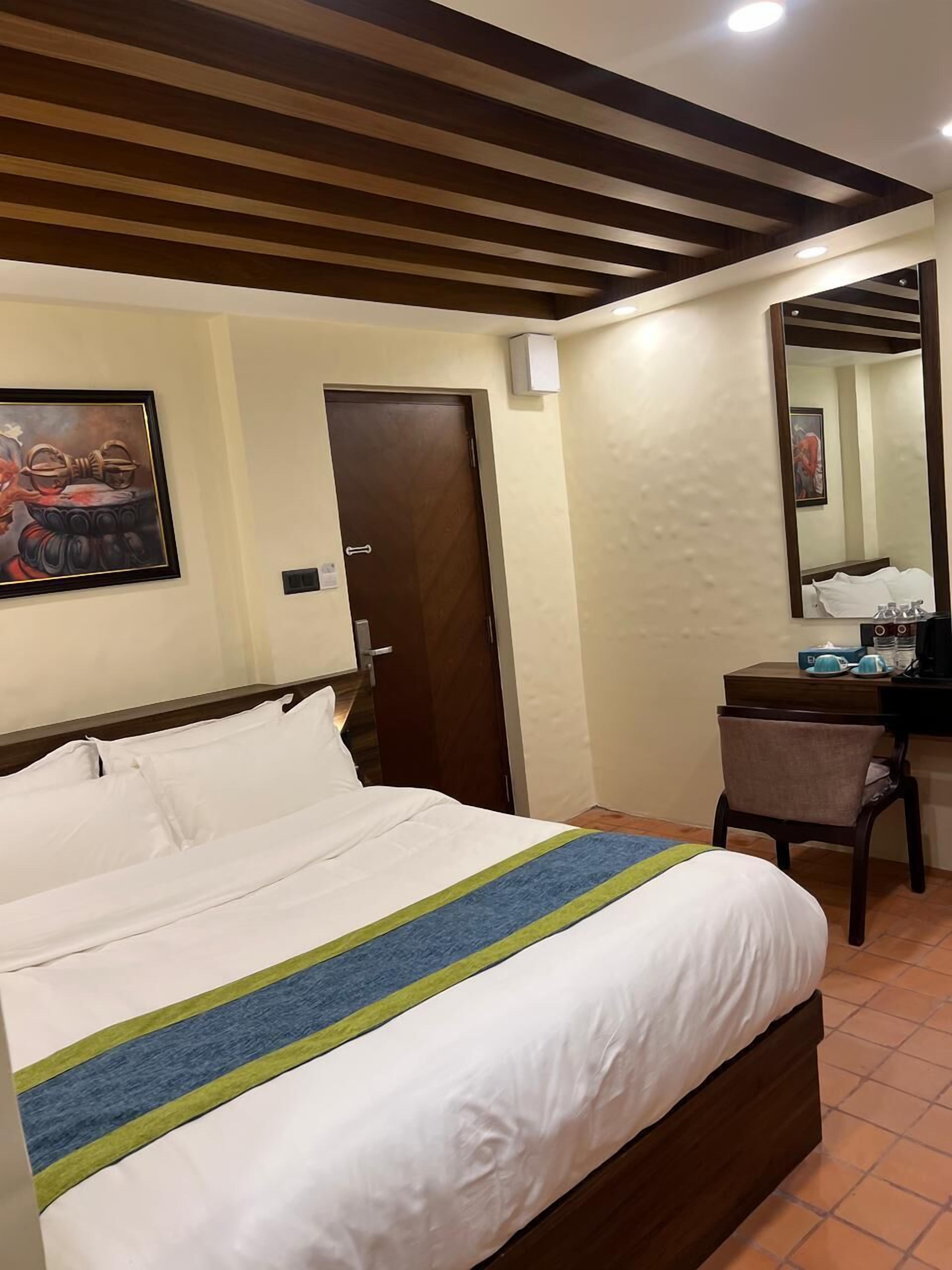 Ein Hotelzimmer mit einem Bett, einem Schreibtisch, einem Stuhl, einer Tür und einem Bild an der Wand.