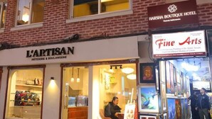 A building with a brick facade, a bakery named 'L'ARTISAN' on the ground floor, and a hotel named 'HARSHA BOUTIQUE HOTEL' above. - Harsha Boutique Hotel (Kathmandu)