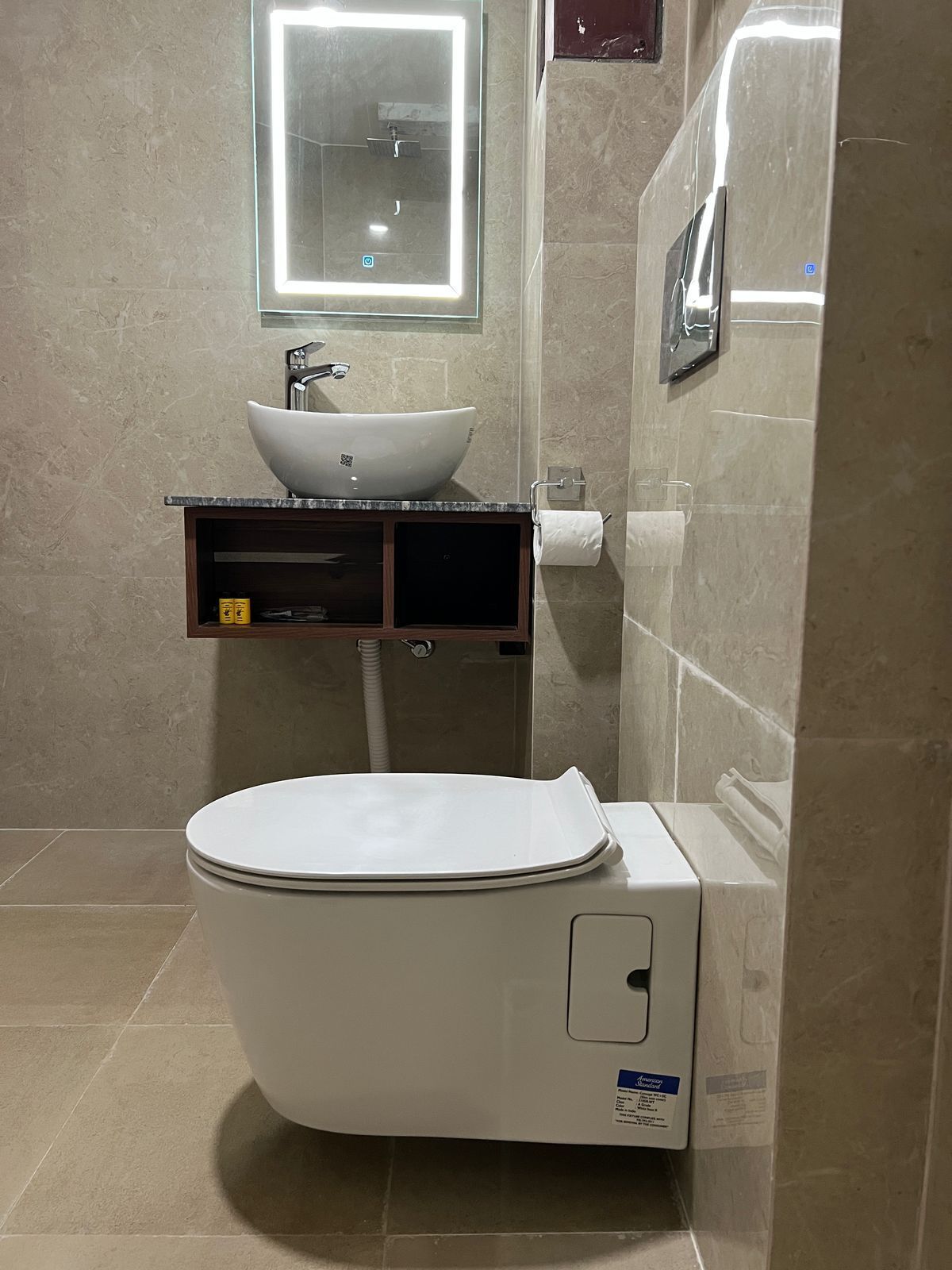 Une salle de bain moderne avec des toilettes blanches, un lavabo sur colonne et un miroir au-dessus du lavabo.