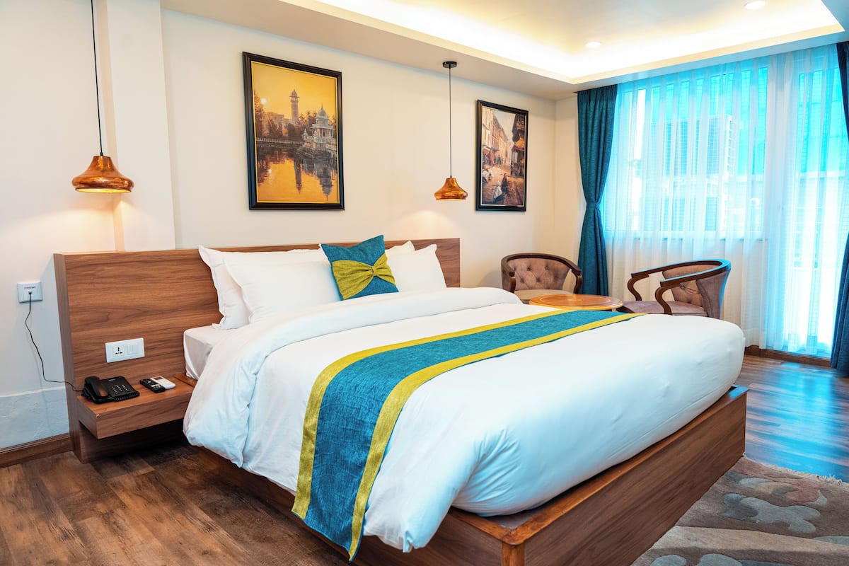 Une chambre d’hôtel avec un lit en bois, une table de chevet avec un téléphone et une chaise.