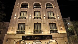 A hotel with a classic architectural style, featuring arched windows and balconies with flower arrangements. - The Meera Hotel (Ujjain)
