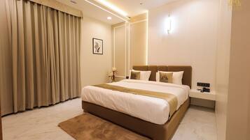 A modern hotel room with a large bed, a bedside table, a nightstand, a wall-mounted light, and a ceiling fan.