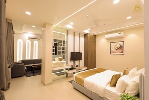 Una habitación de hotel moderna con una cama, un televisor, un escritorio y una zona de estar.