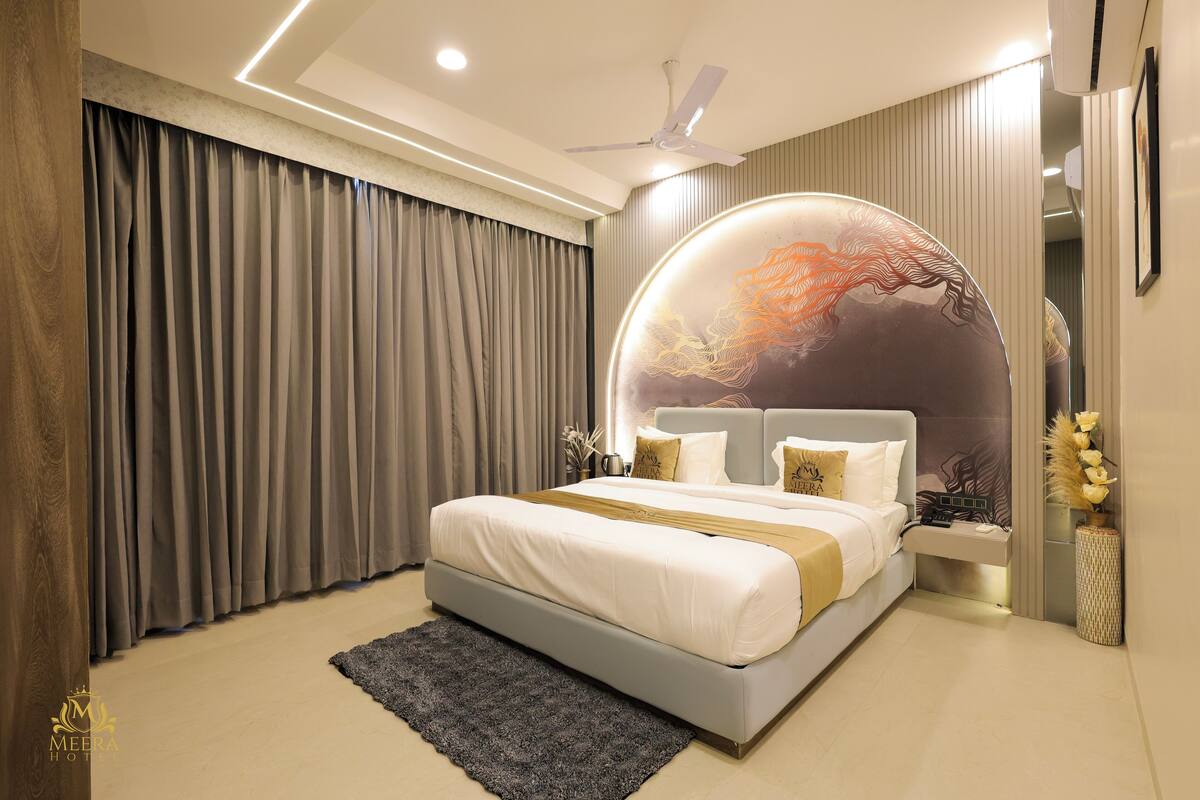 A modern bedroom with a large bed, a ceiling fan, and a decorative wall piece.
