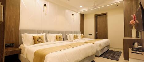 A hotel room with two beds, a wooden nightstand, a desk with a chair, a TV, and a decorative vase.