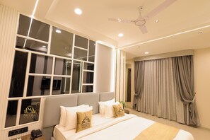 A hotel room with a large bed, a ceiling fan, and a window with multiple panes. - The Meera Hotel (Ujjain)