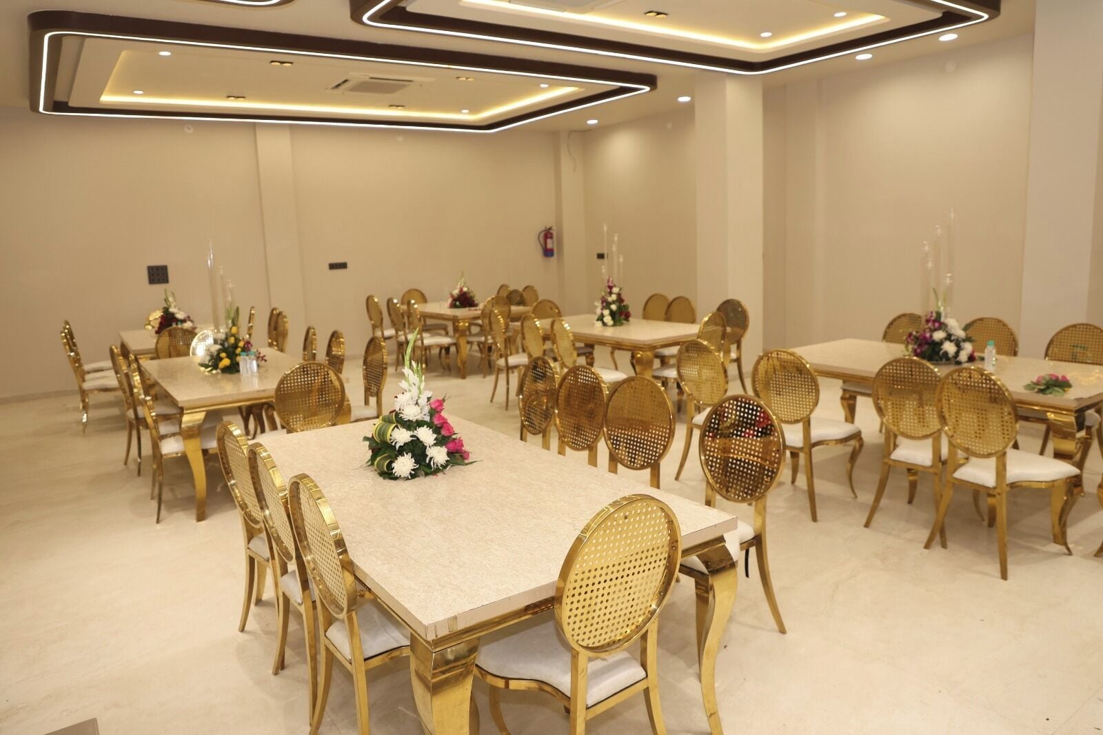 Ein Bankettsaal mit mehreren runden Tischen und Stühlen, jeder Tisch mit einer floralen Dekoration.