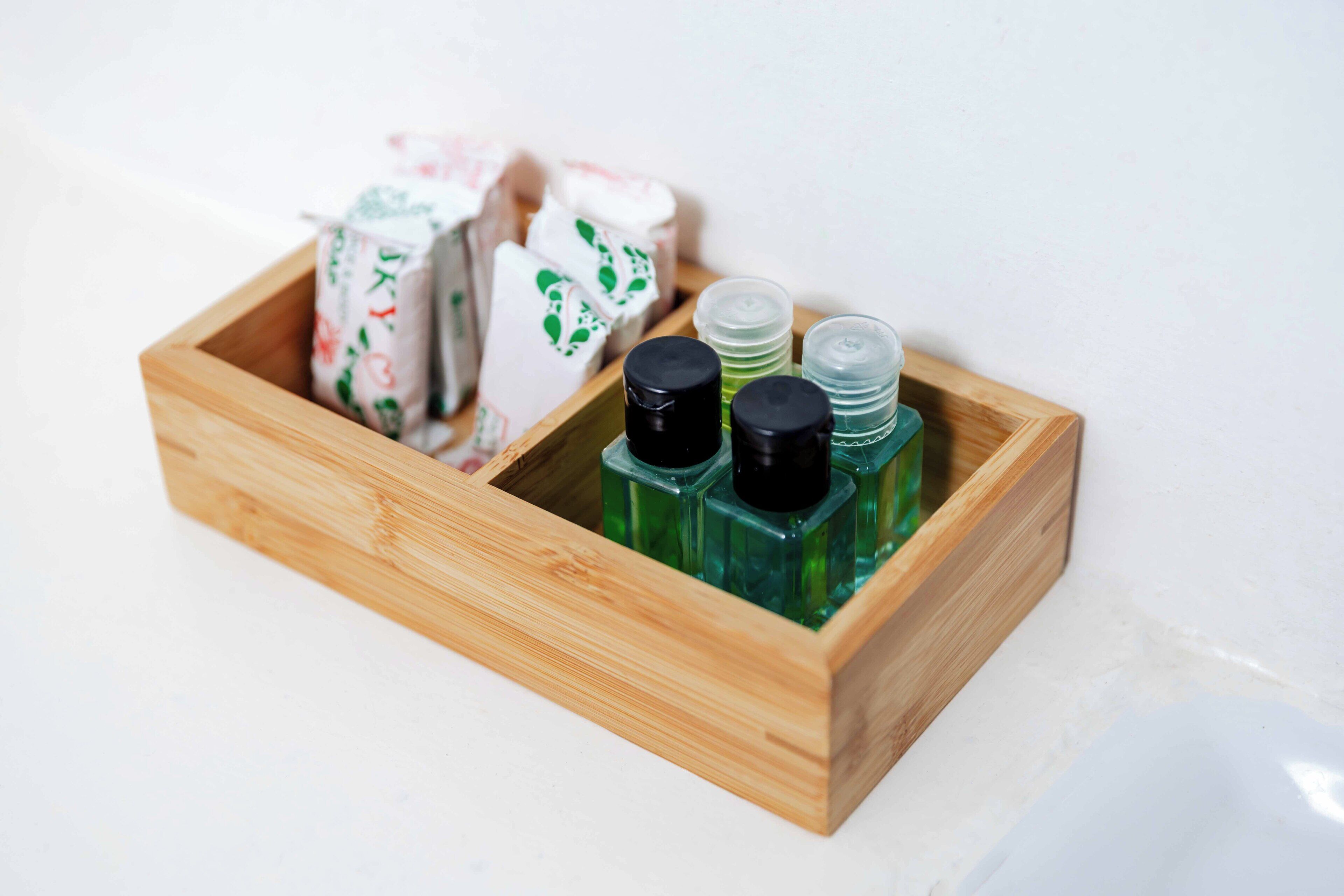 A wooden box containing various toiletries including bottles and soap bars.