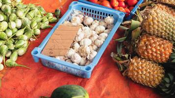 A variety of fresh produce including tomatoes, green beans, corn, and watermelons displayed on a red surface.