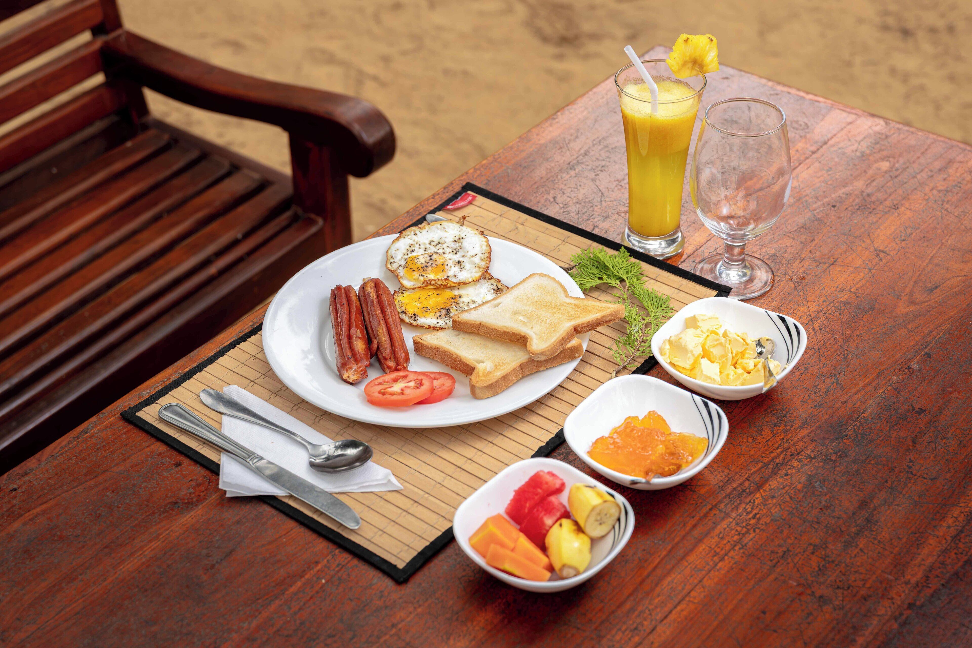A wooden table with breakfast items including toast, eggs, bacon, and fruit.