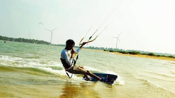 A person windsurfing on a body of water with wind turbines in the background.