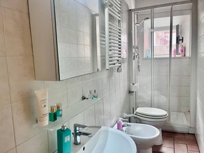 Ein modernes Badezimmer mit einem großen Spiegel, zwei Waschbecken, einer Toilette und einer Duschkabine.