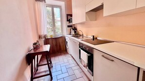 Una cucina compatta con una finestra, un lavello, un fornello e un piccolo tavolo da pranzo.