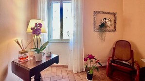 Una stanza con una finestra, una scrivania con una lampada, una sedia e una pianta in vaso.