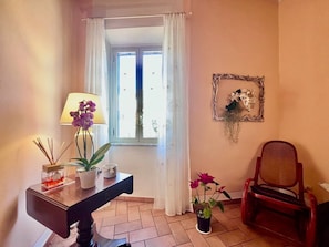 A room with a window, a desk with a lamp, a chair, and a potted plant.