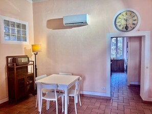 Ein Zimmer mit einem weißen Tisch, Stühlen, einer Klimaanlage, einer Uhr und einem Fenster mit Blick.