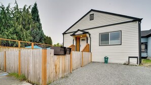 Une maison de plain-pied avec une clôture en bois, une allée en gravier et un petit jardin devant.