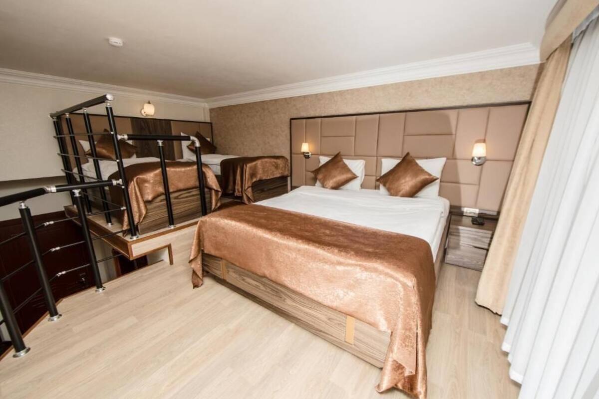 Une chambre d’hôtel avec un grand lit, un escalier et une table de chevet avec une lampe.