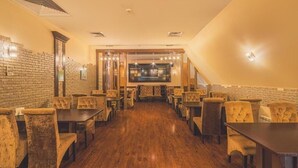 Un restaurante con suelo de madera, paredes de ladrillo y sillas tapizadas.