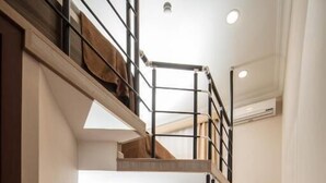 Una escalera conduce a una zona superior con piso de madera y alfombra roja.