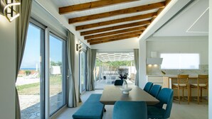 Een modern interieur met een grote eettafel, blauwe stoelen en uitzicht op het omliggende landschap.