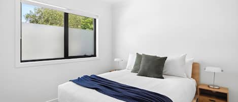 Camera da letto con un letto grande, un comodino, una finestra e vista sugli alberi.