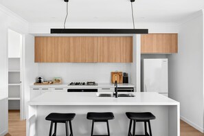 Una cucina moderna con mobili bianchi, un'isola centrale con sgabelli da bar e un forno integrato.