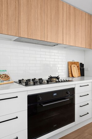 A modern kitchen with white cabinets, a black oven, and a gas stove.