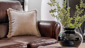 A modern living room with a leather sofa, a vase with green foliage, and two books on a wooden coffee table. - St Helens I Stunning Family Townhouse in Geelong (Rippleside)