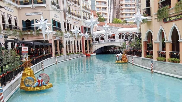 An indoor swimming pool with a bridge, surrounded by multi-story buildings with balconies and shops. - Deluxe 1BR 27th floor in Taguig/BGC w/balcony, amazing view of bay, wi-fi+55" TV (Taguig)