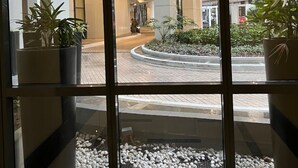 A modern building with a glass entrance, potted plants, and a pebbled area. - Deluxe 1BR 27th floor in Taguig/BGC w/balcony, amazing view of bay, wi-fi+55" TV (Taguig)