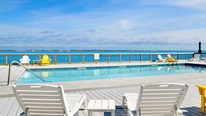 A pool area with a view of the ocean, deck chairs, and a lifeguard stand.